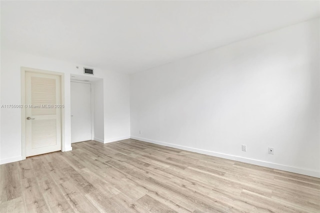 unfurnished room with light wood finished floors, baseboards, and visible vents