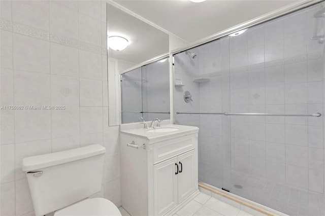 full bath featuring toilet, tile patterned floors, vanity, a shower stall, and tile walls