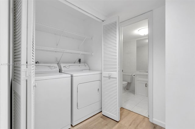 clothes washing area with light wood-type flooring, laundry area, and separate washer and dryer