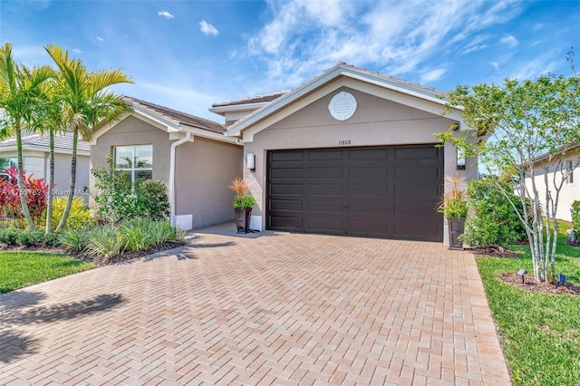 ranch-style house with a garage, decorative driveway, and stucco siding