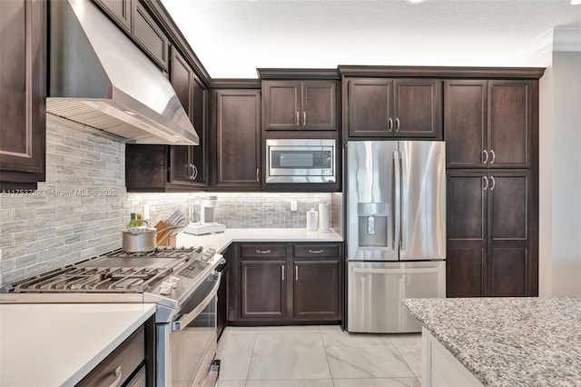kitchen with marble finish floor, stainless steel appliances, backsplash, dark brown cabinets, and under cabinet range hood