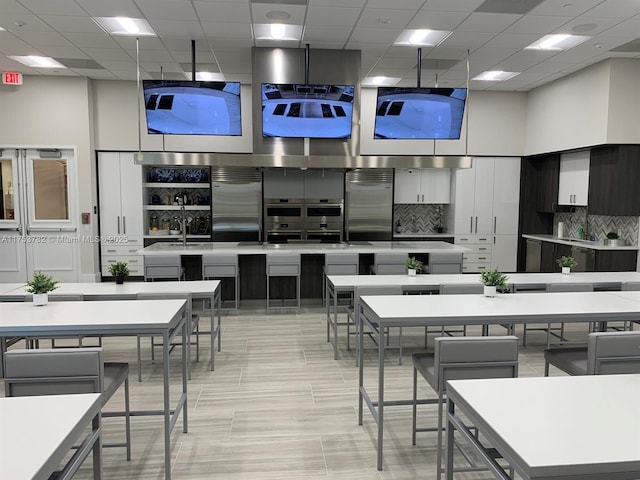 kitchen with built in refrigerator, modern cabinets, a high ceiling, and backsplash