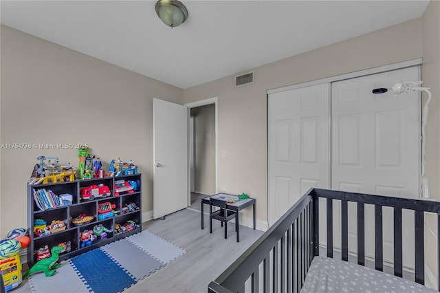 bedroom with baseboards, visible vents, a closet, and wood finished floors