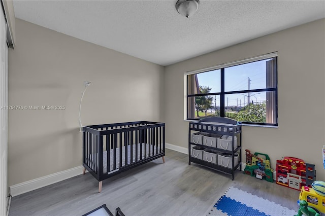 bedroom with a textured ceiling, baseboards, and wood finished floors