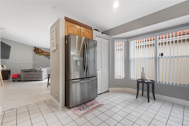 kitchen featuring baseboards, light tile patterned flooring, and stainless steel fridge with ice dispenser