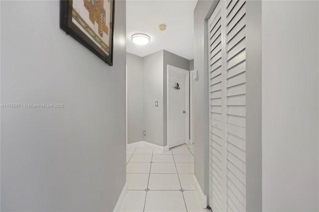 hall featuring light tile patterned floors and baseboards