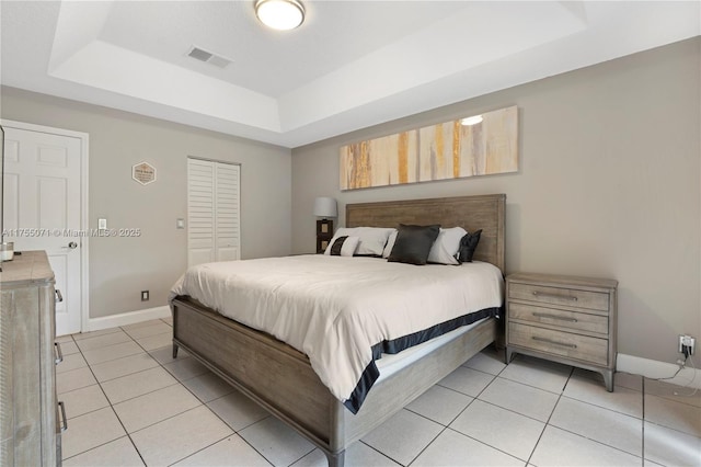 bedroom with baseboards, visible vents, a tray ceiling, and light tile patterned flooring