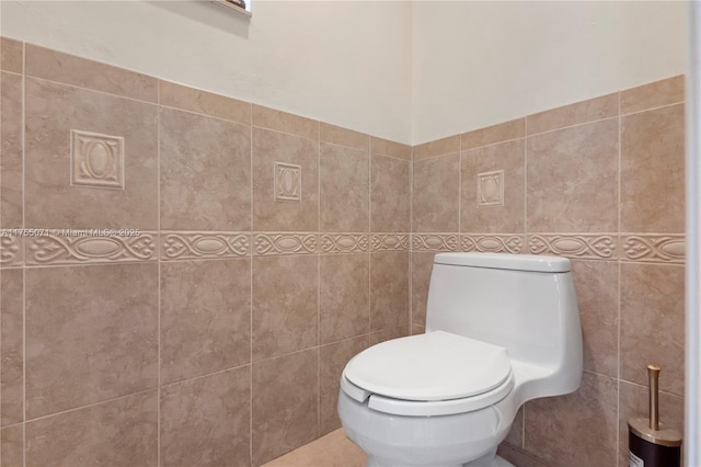 bathroom featuring toilet and tile walls