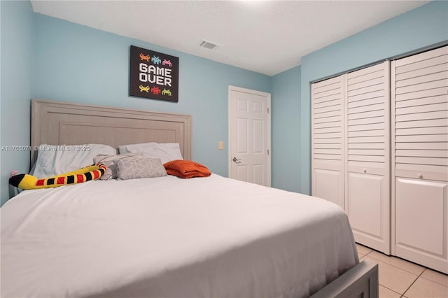 bedroom featuring a closet, visible vents, a textured ceiling, and light tile patterned floors