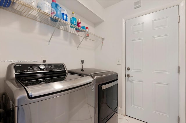 washroom featuring light tile patterned floors, laundry area, visible vents, and washer and dryer