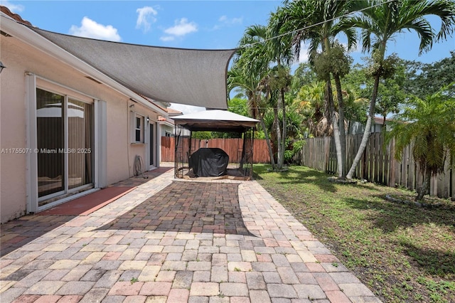 view of patio with a gazebo, a fenced backyard, and a grill