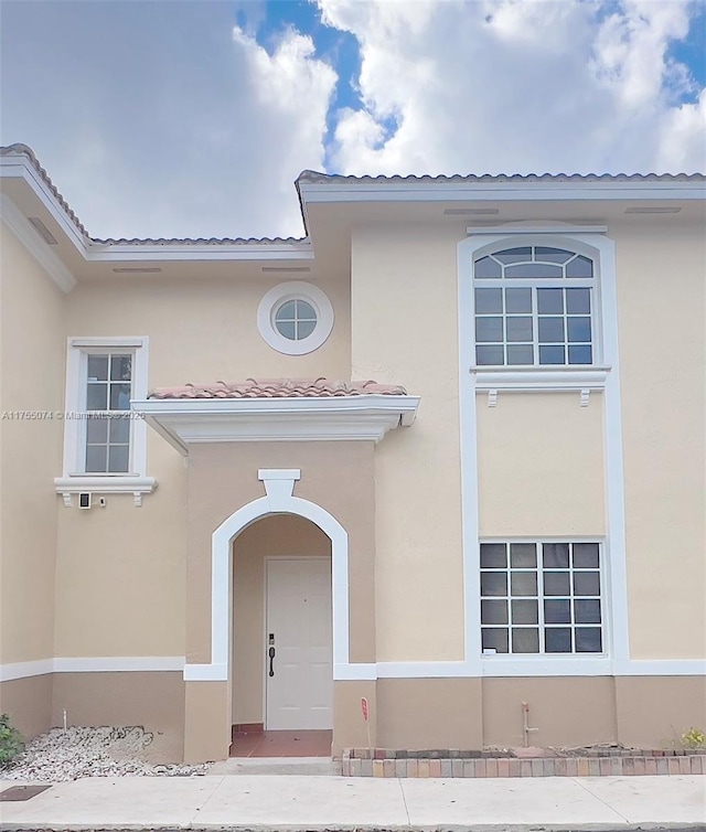 doorway to property featuring a tile roof and stucco siding