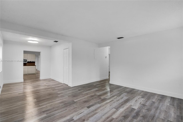 spare room with visible vents, baseboards, and wood finished floors