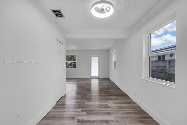 spare room featuring baseboards, visible vents, a textured ceiling, and wood finished floors