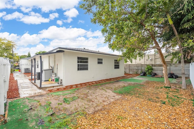 rear view of house featuring central air condition unit, a fenced backyard, and stucco siding