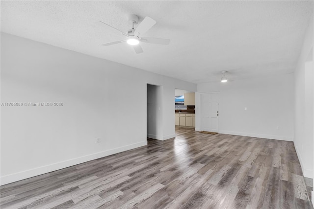 unfurnished room featuring ceiling fan, a textured ceiling, baseboards, and wood finished floors