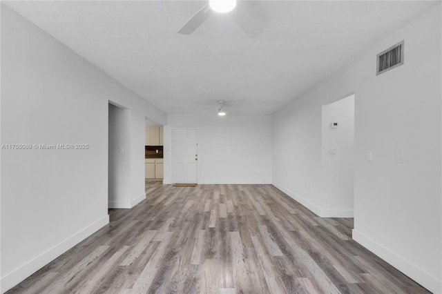 unfurnished living room featuring light wood-type flooring, visible vents, and a ceiling fan