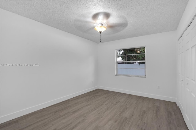 spare room with a textured ceiling, baseboards, and wood finished floors