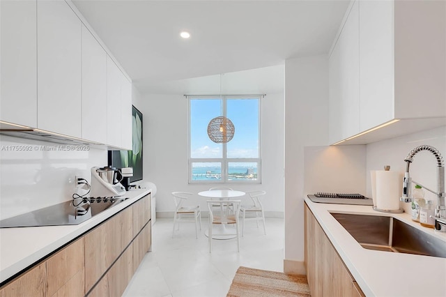 kitchen with modern cabinets, black electric stovetop, and a sink