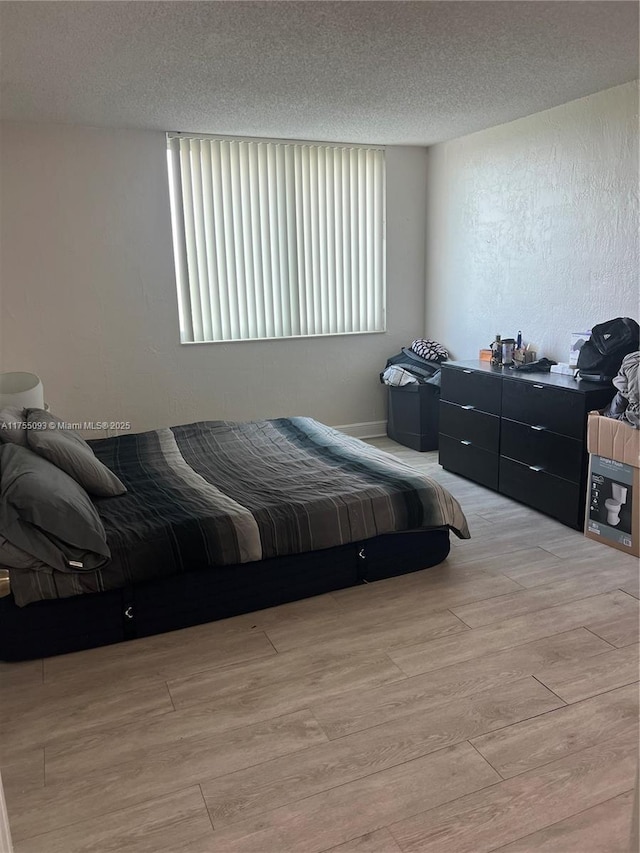 bedroom with a textured ceiling and wood finished floors