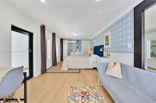 bedroom featuring light wood-style floors, baseboards, and wallpapered walls