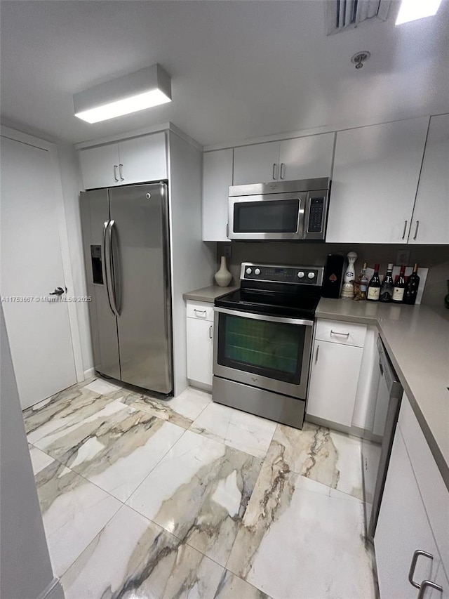 kitchen featuring marble finish floor, stainless steel appliances, visible vents, and white cabinets