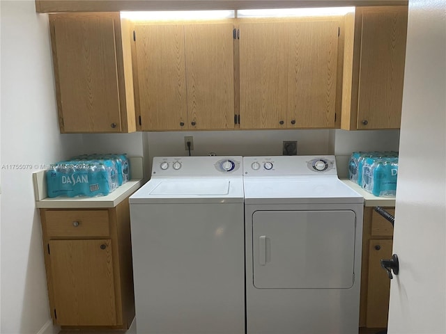 clothes washing area featuring washing machine and clothes dryer and cabinet space