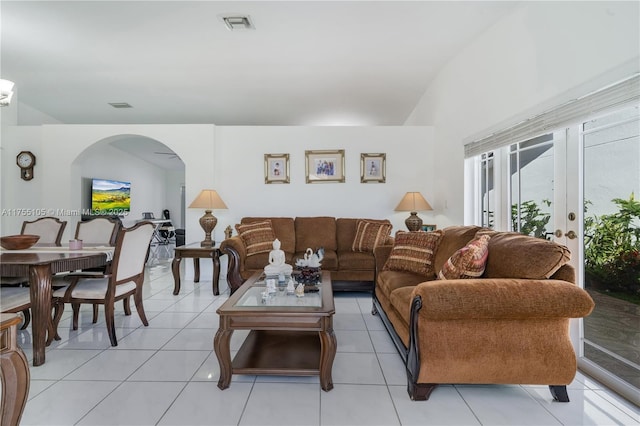 living room with light tile patterned floors, visible vents, arched walkways, and french doors