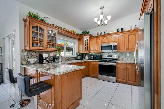 kitchen featuring lofted ceiling, appliances with stainless steel finishes, brown cabinets, a peninsula, and light tile patterned flooring