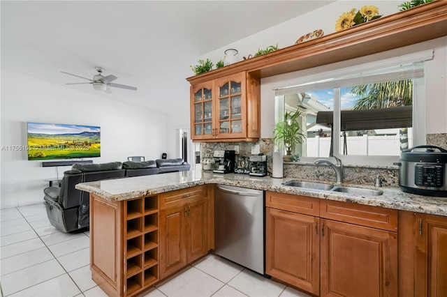 kitchen featuring brown cabinetry, a sink, light stone counters, and stainless steel dishwasher