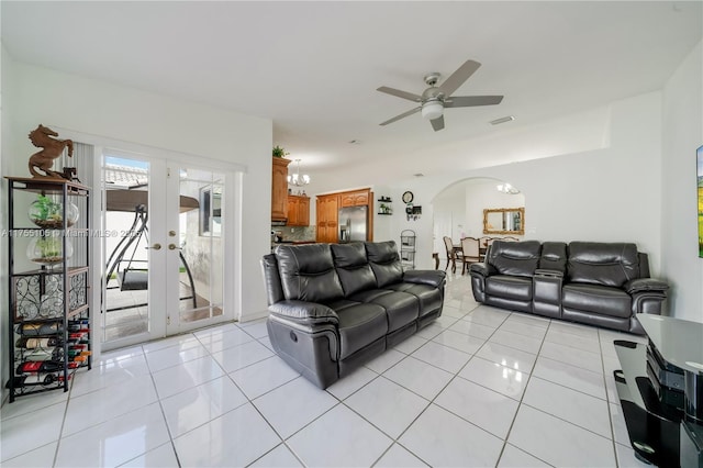 living area featuring light tile patterned floors, french doors, ceiling fan with notable chandelier, and arched walkways