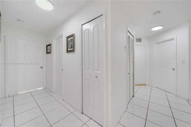 corridor with visible vents, baseboards, and light tile patterned floors