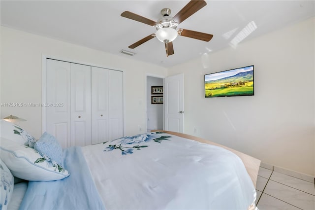 bedroom with a closet, visible vents, ceiling fan, and light tile patterned floors