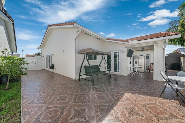 rear view of property featuring a ceiling fan, a tile roof, french doors, a patio area, and stucco siding