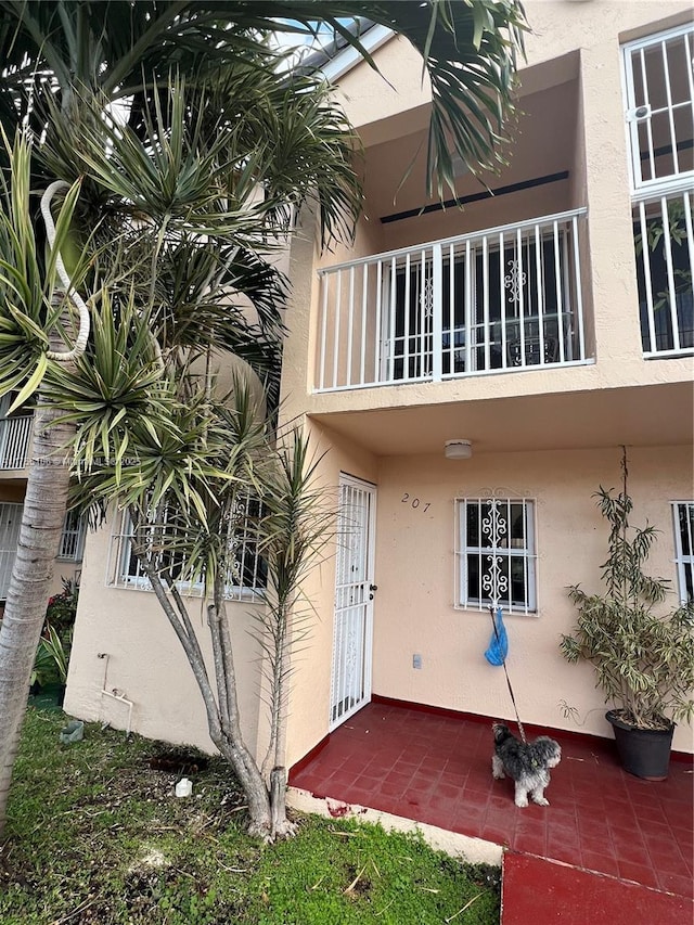 doorway to property with a balcony and stucco siding