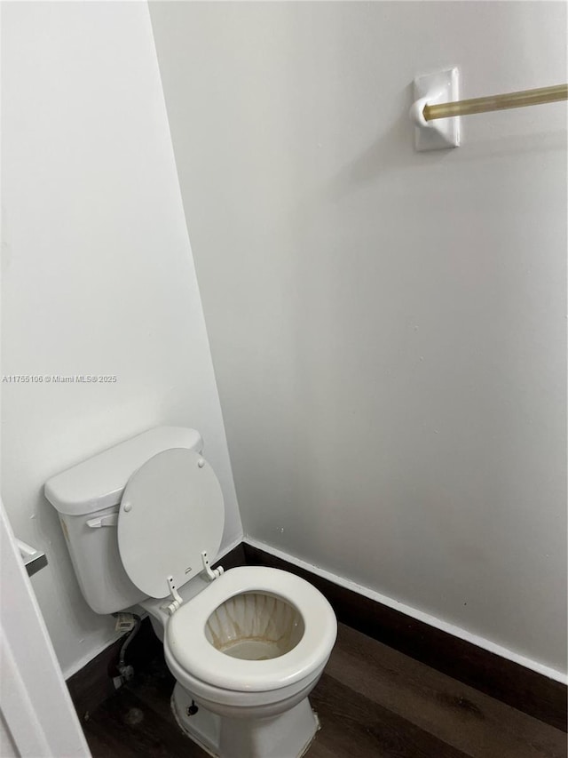 bathroom with toilet, baseboards, and wood finished floors