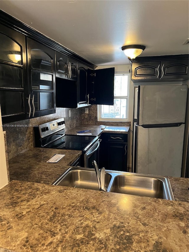 kitchen with a sink, dark countertops, stainless steel appliances, and dark cabinets