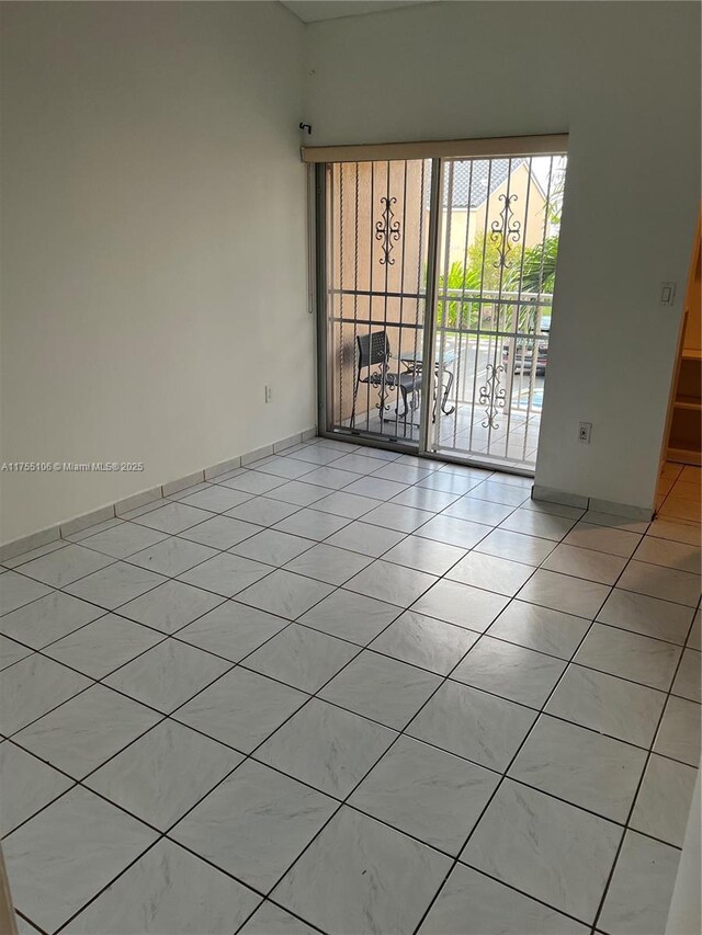 spare room featuring light tile patterned floors and baseboards