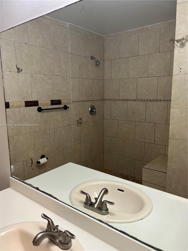 bathroom with tiled shower and vanity