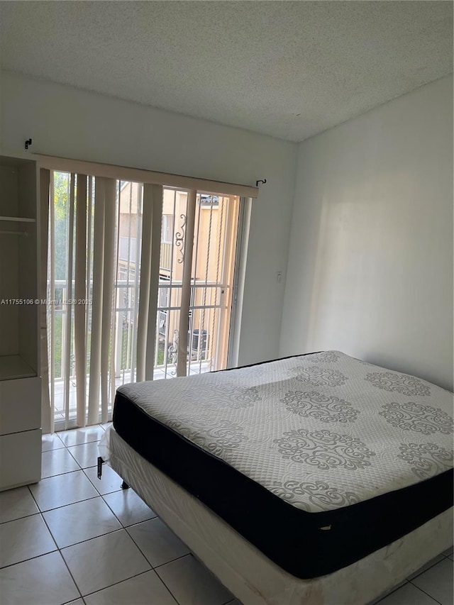 bedroom featuring light tile patterned floors, access to outside, and a textured ceiling