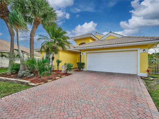 view of front of property featuring an attached garage, fence, decorative driveway, and stucco siding