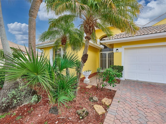 exterior space featuring a garage, a tile roof, and stucco siding