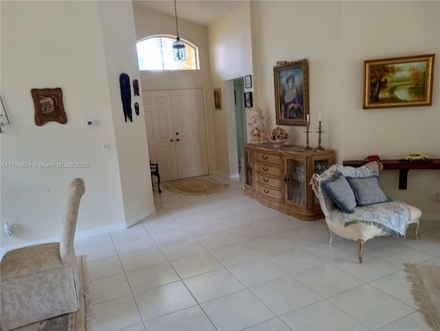 entrance foyer featuring light tile patterned floors, a towering ceiling, and baseboards