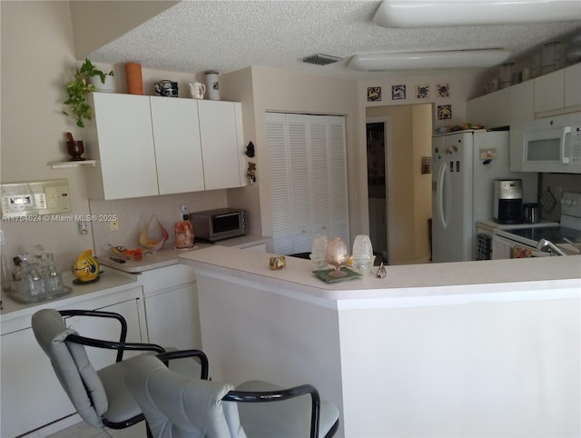 kitchen with light countertops, white cabinetry, a textured ceiling, white appliances, and a peninsula