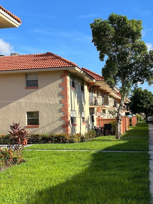 view of property exterior with a yard, a tiled roof, and stucco siding