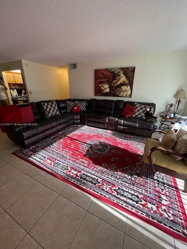 tiled living room featuring visible vents and a textured ceiling