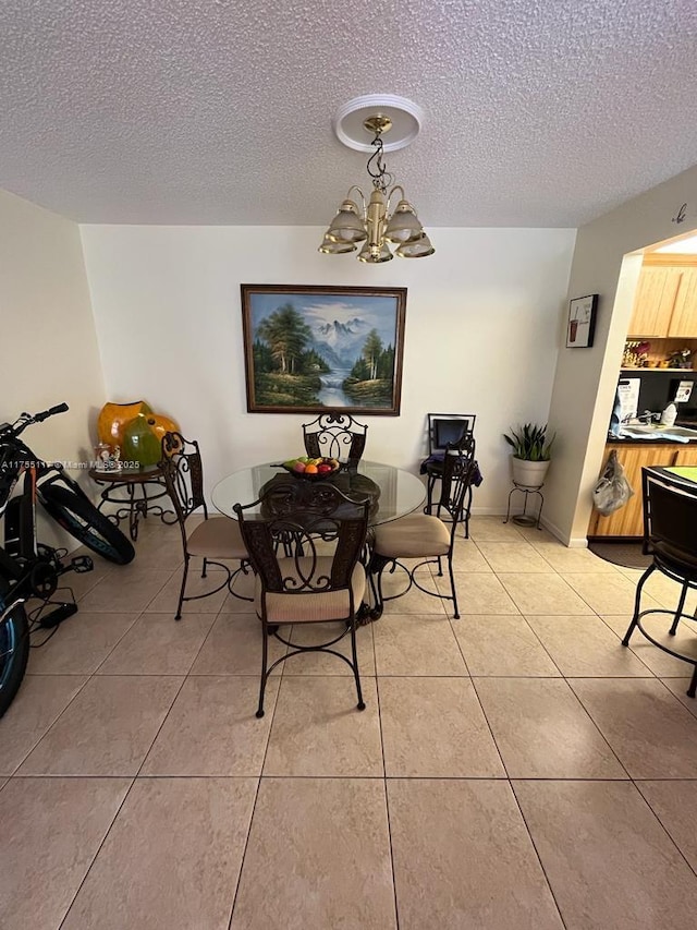 dining space with a chandelier, light tile patterned floors, and a textured ceiling