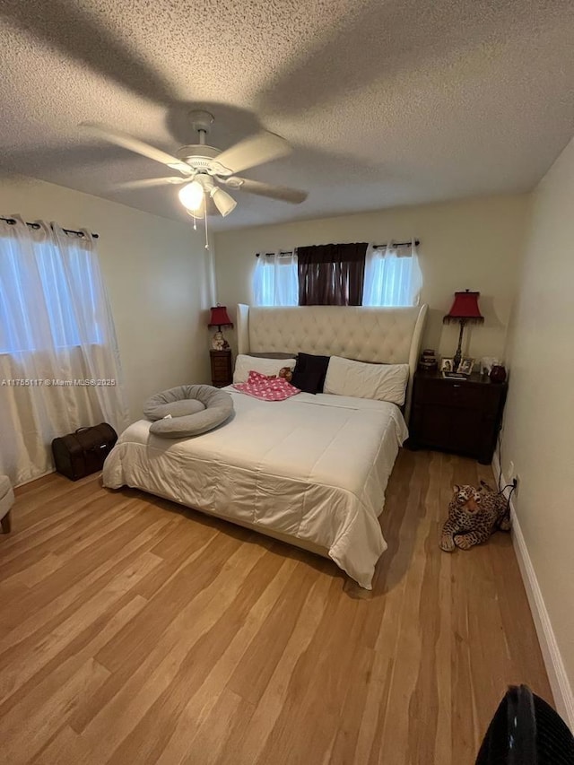 bedroom with baseboards, a textured ceiling, a ceiling fan, and wood finished floors