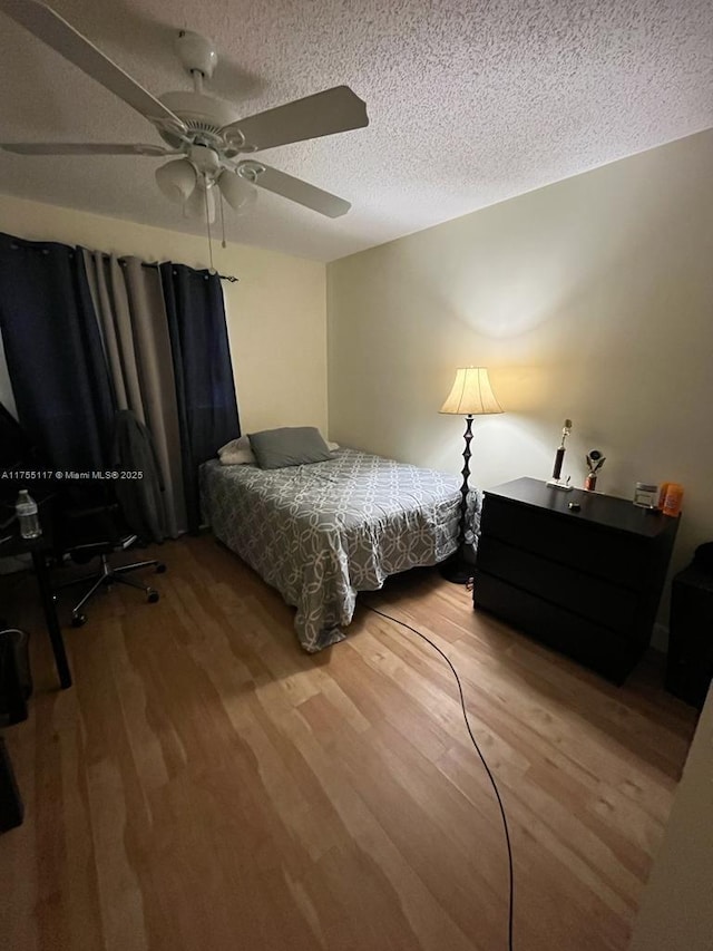 bedroom with a textured ceiling, wood finished floors, and a ceiling fan