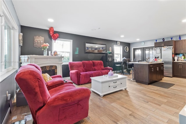 living area featuring light wood-style flooring, a fireplace, a wealth of natural light, and recessed lighting